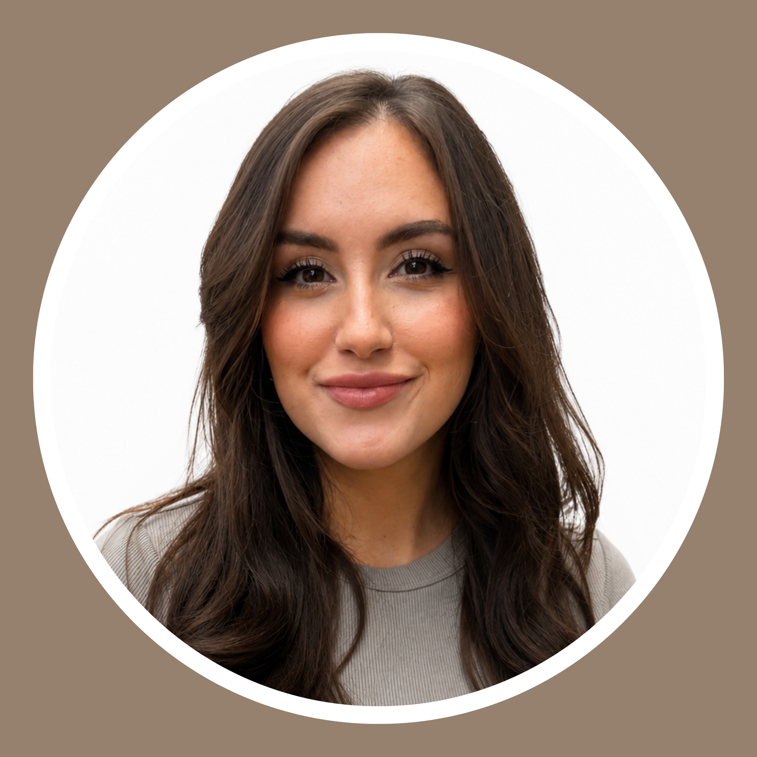 Close-up of a woman's face with long, styled brown hair, brown eyes, and a light gray top, smiling softly, with a background featuring a white semi-circle and brown surrounding area.