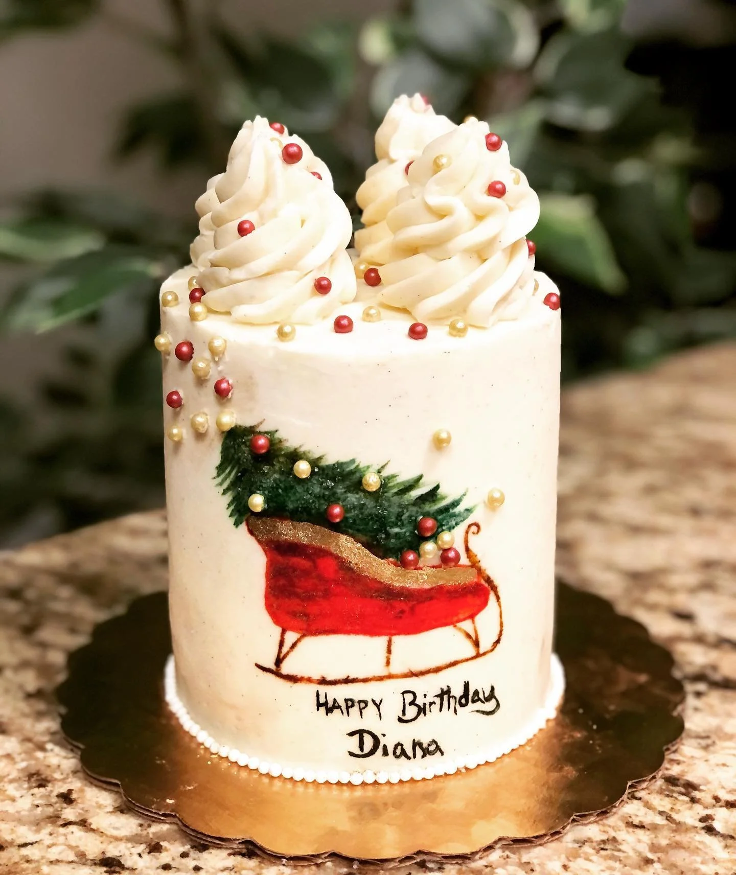 A white birthday cake decorated with swirl frosting, red and gold edible beads, and a Christmas stocking design. The cake has a message that says 'Happy Birthday Diana'.