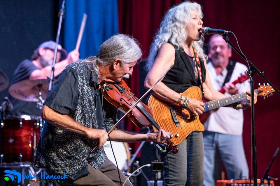 Dusty performing with The LoveNotes, joined by Floyd Fronius on fiddle and Tim Cook on bass — part of the rich live sound that brought Dusty’s original songs to the stage.