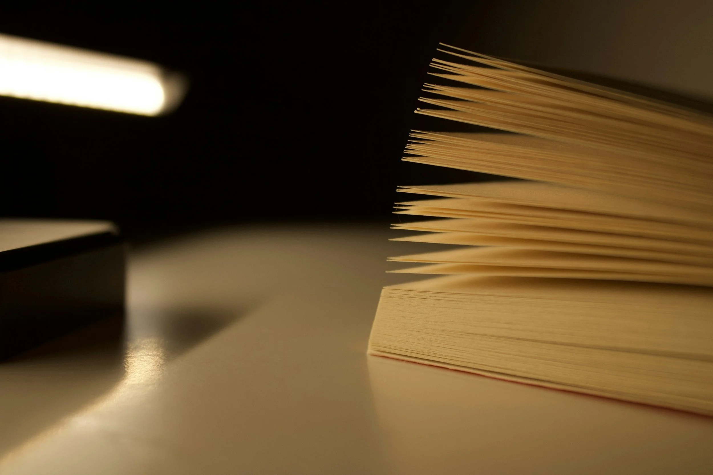 Close-up of a stack of beige papers on a reflective surface with a black background.