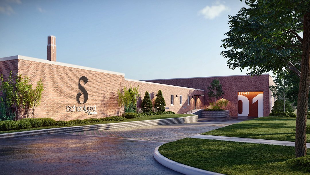 Exterior view of the Schoolyard Studio building with a brick facade, landscaping, trees, and a stage entrance labeled 'Stage 01'.