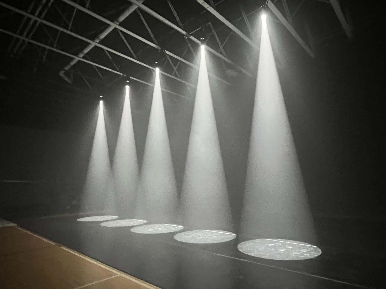 Stage with five spotlights shining downward, each spotlight illuminating a circular pattern on the floor.