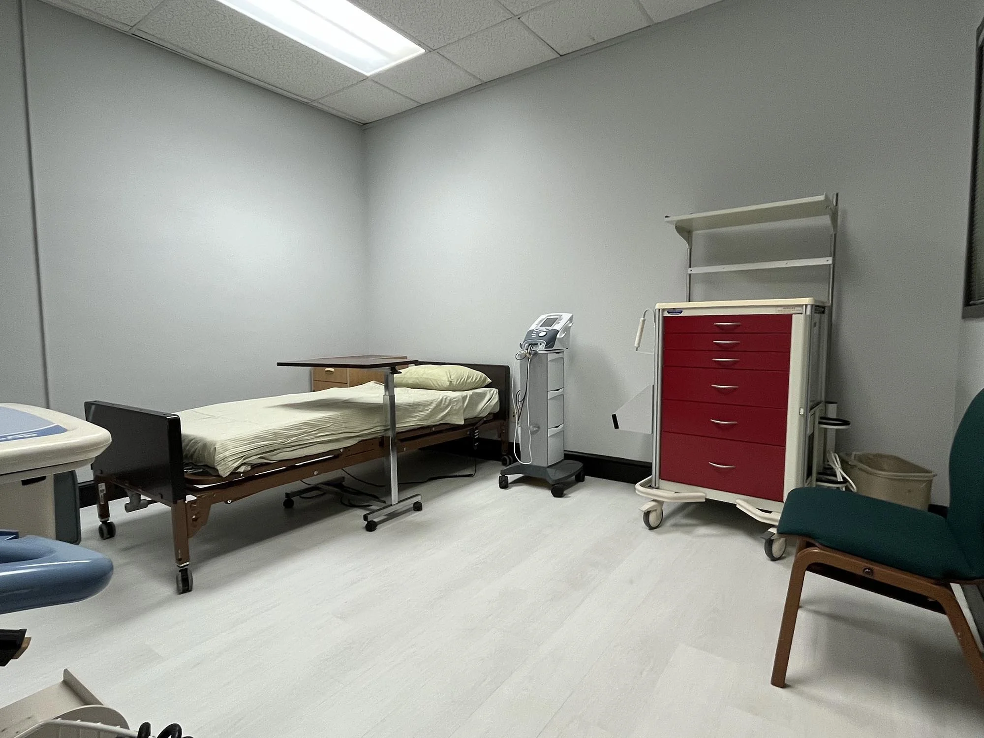 A hospital or clinic room with a bed, medical equipment, and chairs.