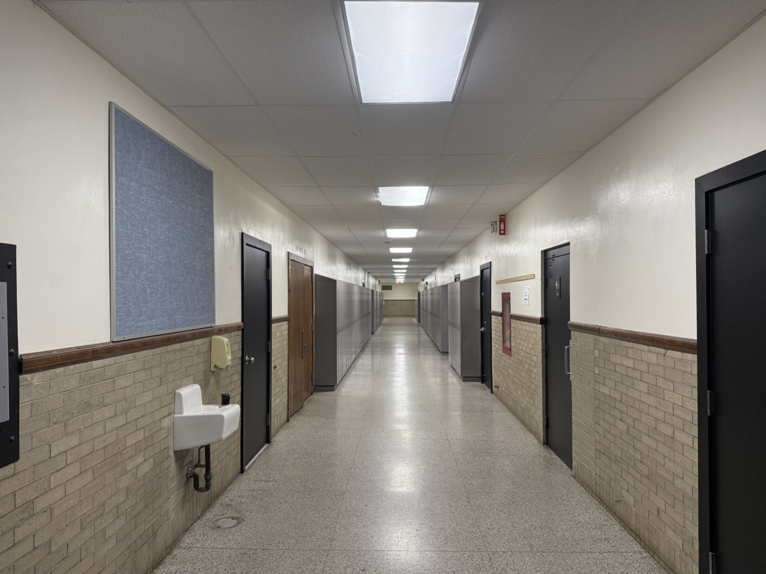 School hallway with lockers, doors, and a water fountain.