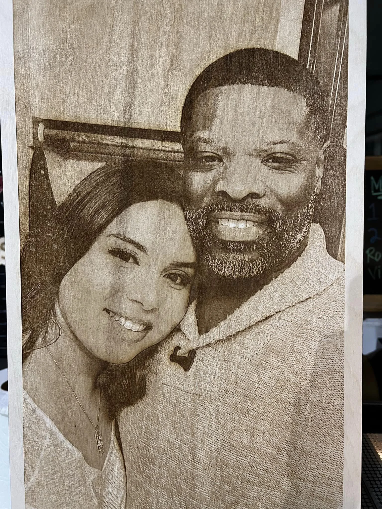 A black and white photo of a smiling couple close together, with the woman on the left and the man on the right, both looking at the camera.