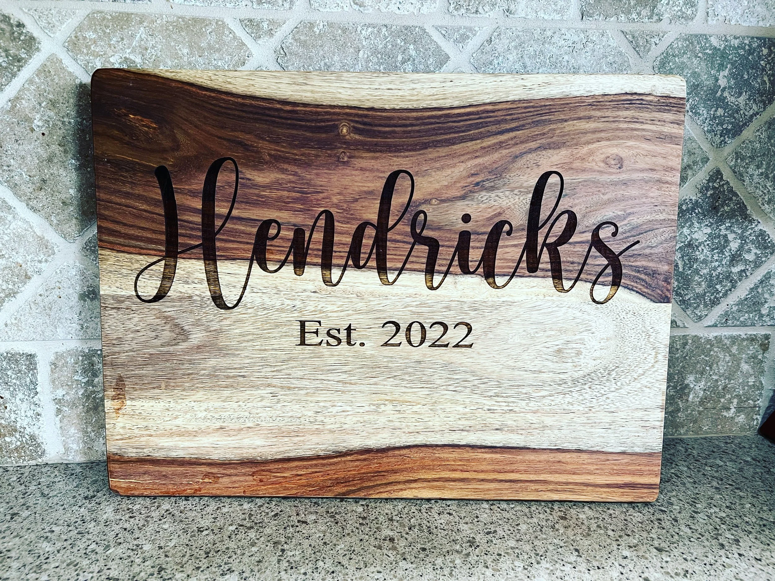 Wooden sign with the word Hendricks in cursive and Est. 2022 written below.