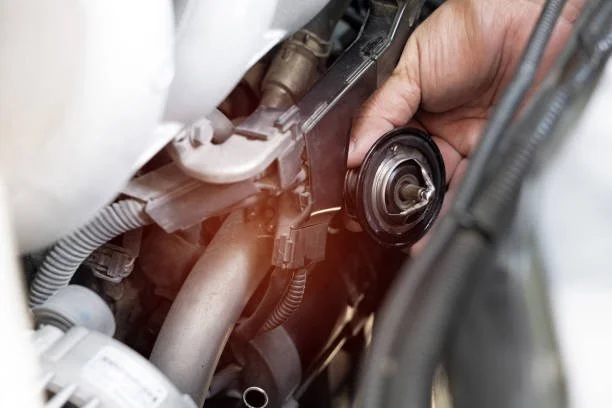 Close-up image of a tech working on an automotive thermostat