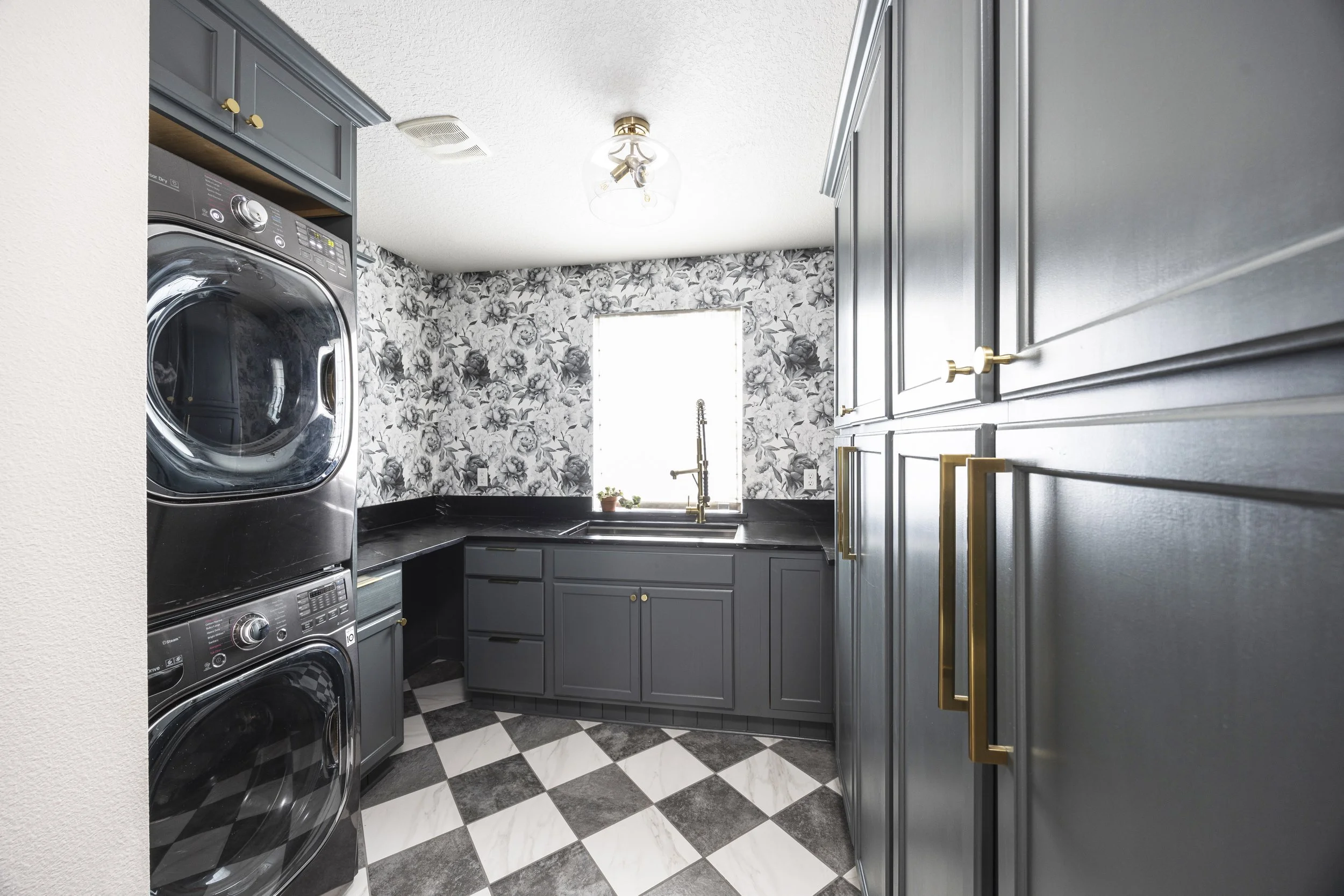 After renovation: Pewter green cabinetry with brass hardware and black countertops with peony wallpaper.