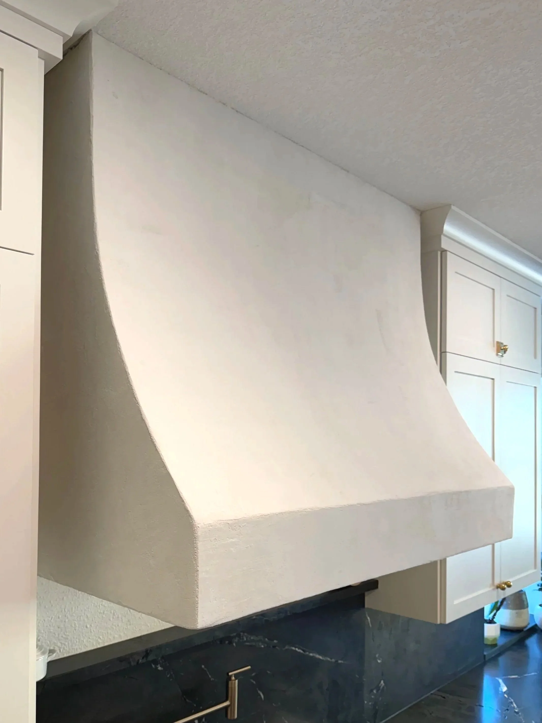Custom sculpted plaster range hood over dark stone counter, Portland, Oregon