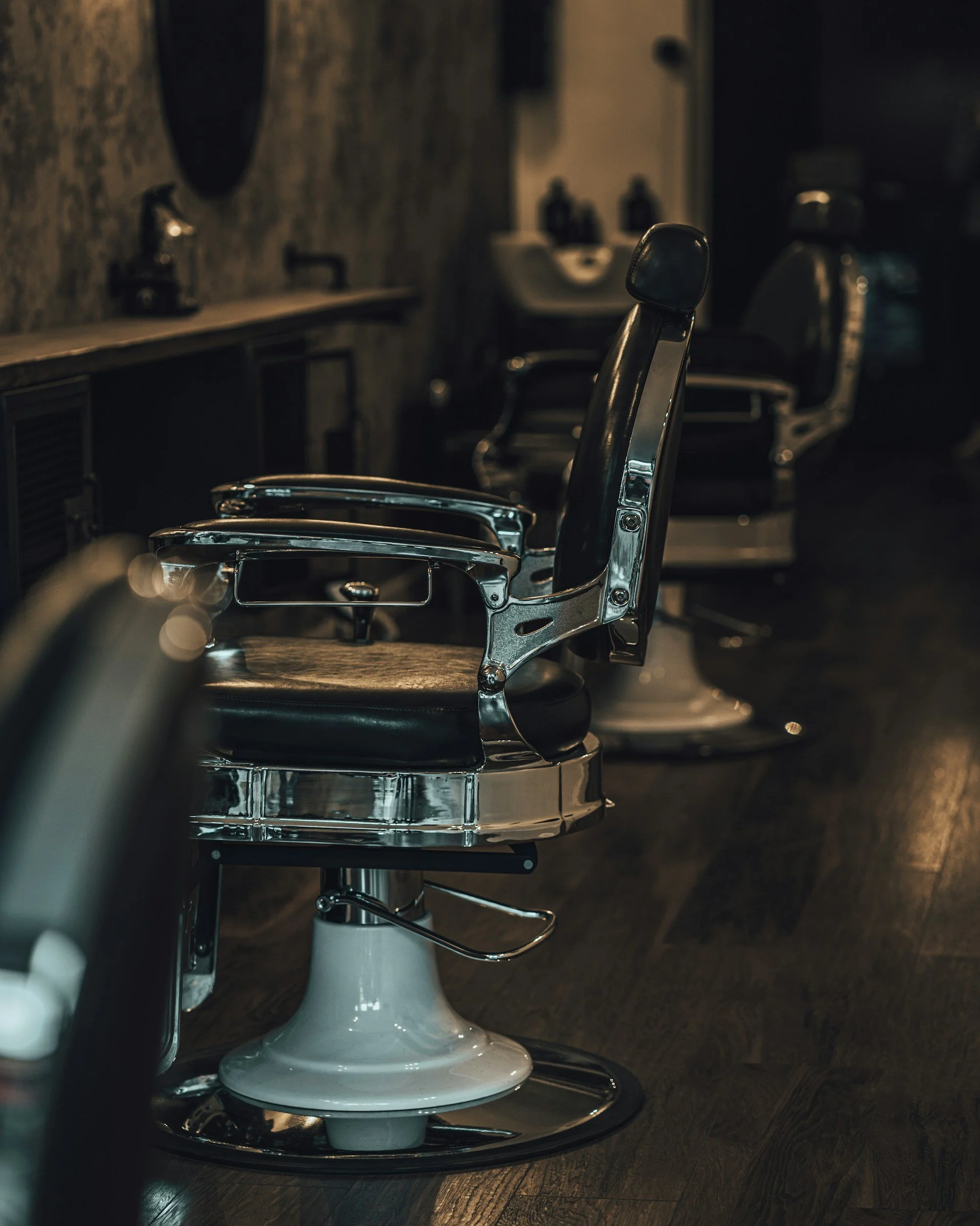 Leere Friseur-Stühle in einem Friseursalon, dunkle Beleuchtung, moderner Stil.