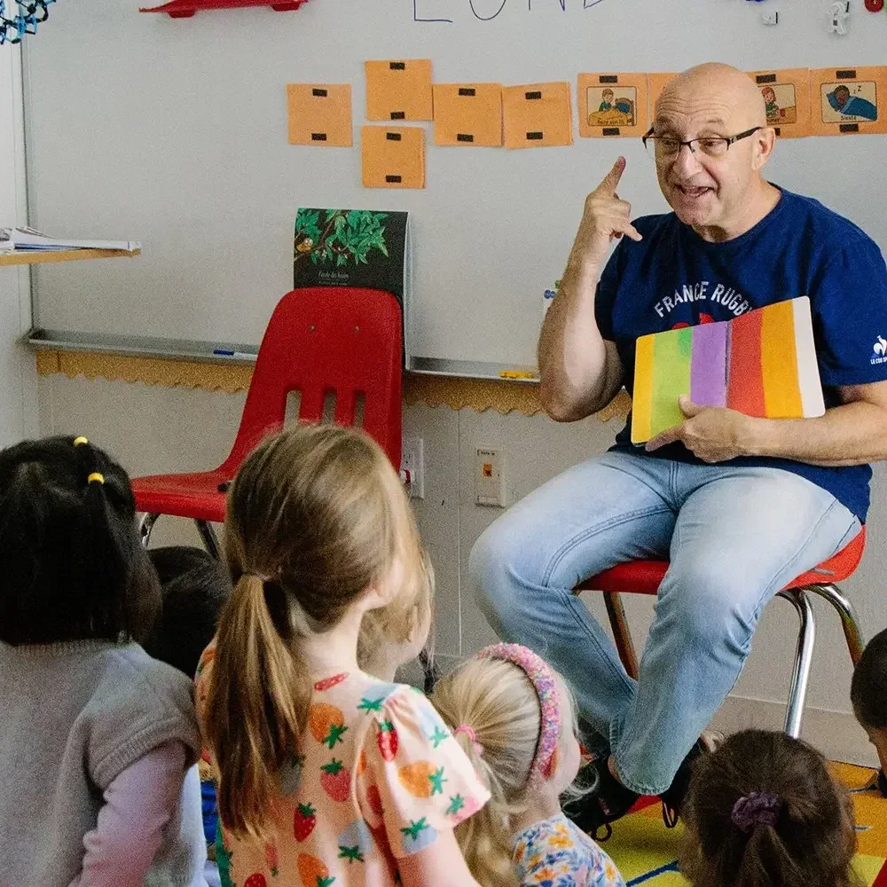 Teacher reading a picture book to preschoolers seated on the floor