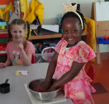 Smiling FASPS preschool students exploring a sensory activity in the classroom