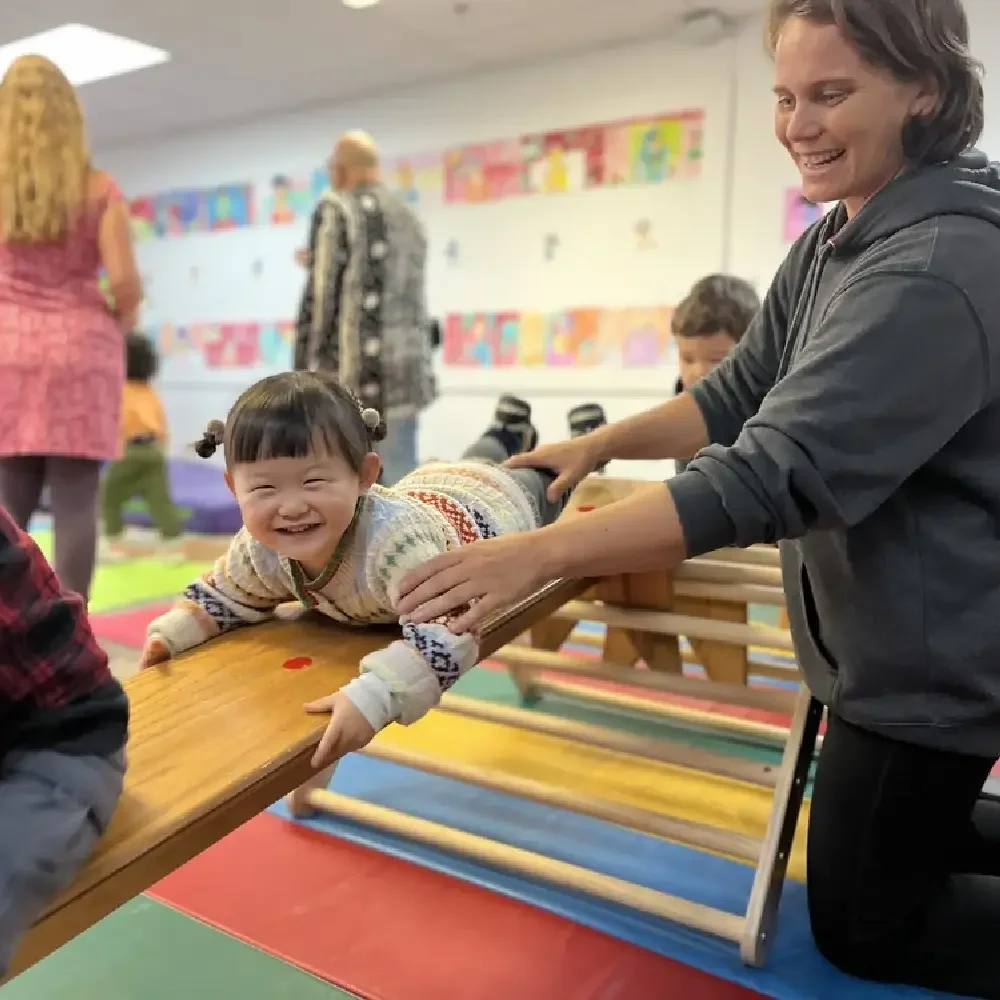 Young girl smiling during a group activity with her teacher