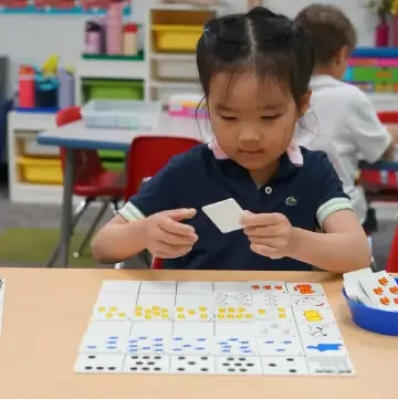 Young girl working with number cards and counters in math class
