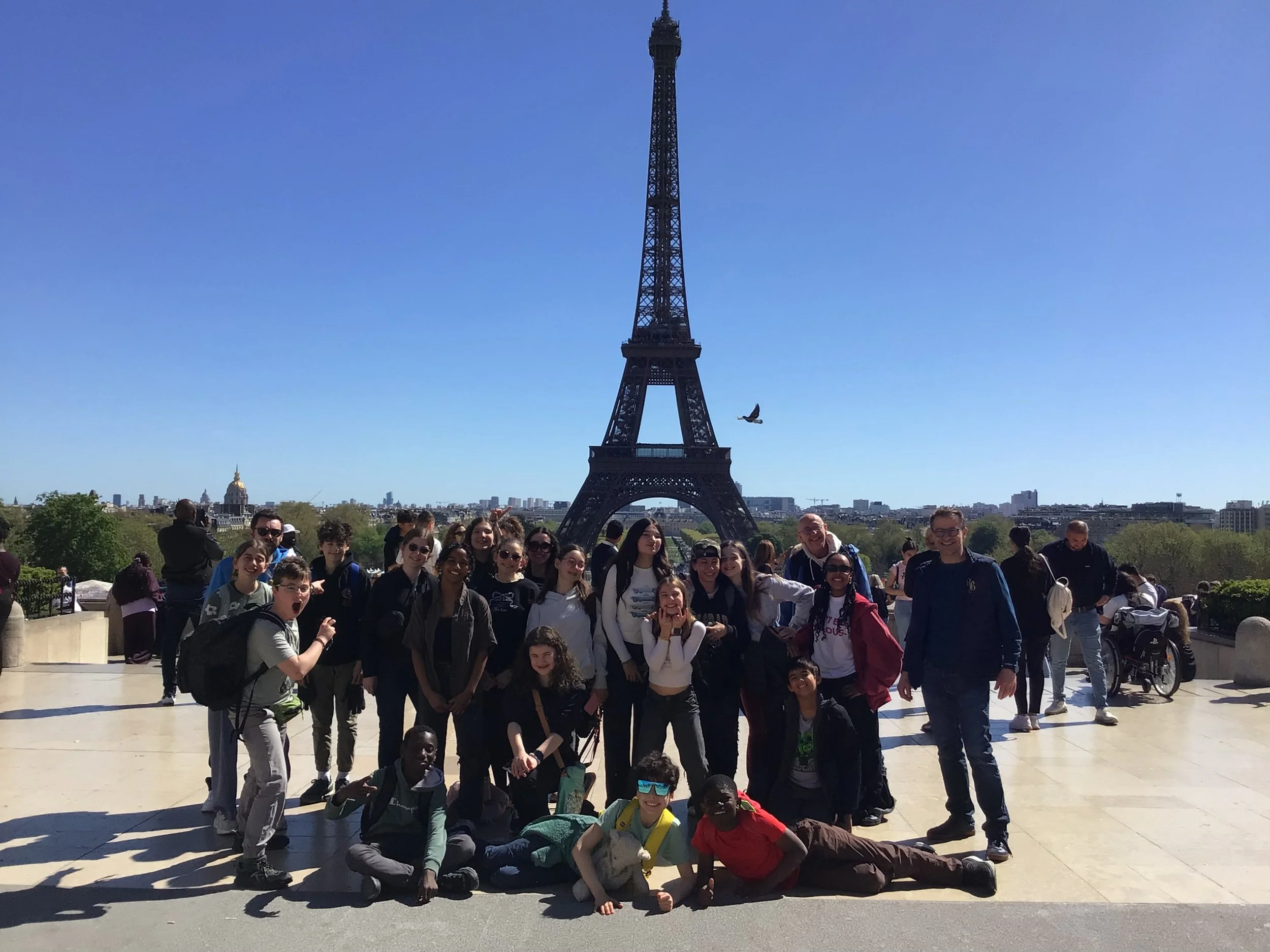 A group of people, including children and adults, posing in front of the Eiffel Tower in Paris, France.