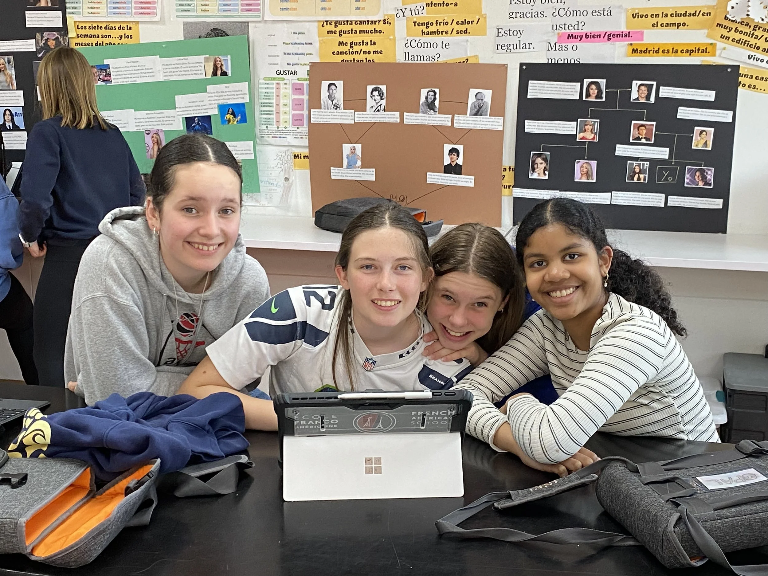 A classroom filled with students sitting at desks, focusing on their work with open textbooks and notebooks, in a classroom with cabinets and sinks in the background.