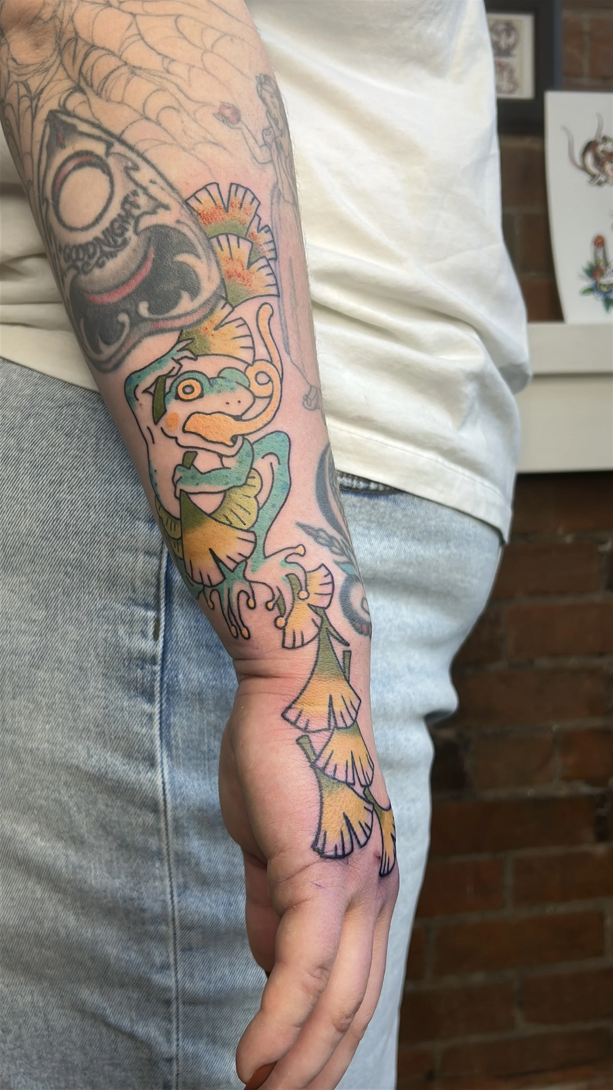 Colorful tattoo of a chameleon on the person's arm.