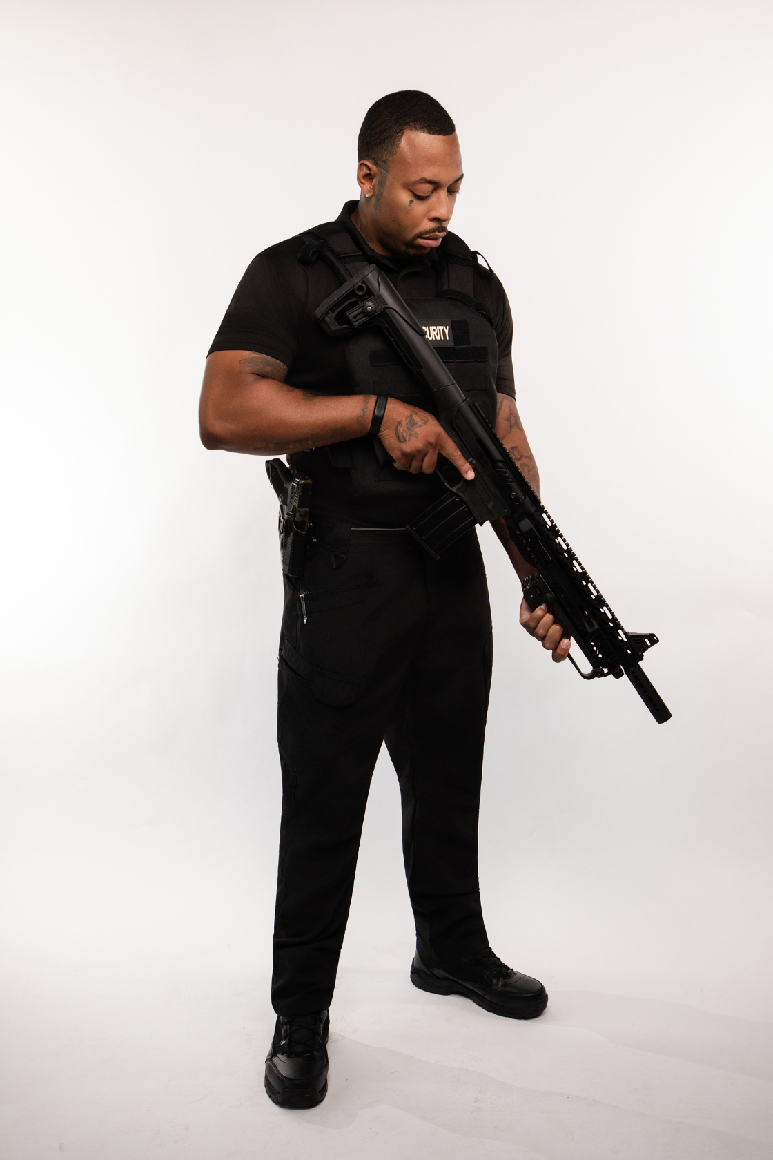 A security officer holding a rifle while standing against a white background.