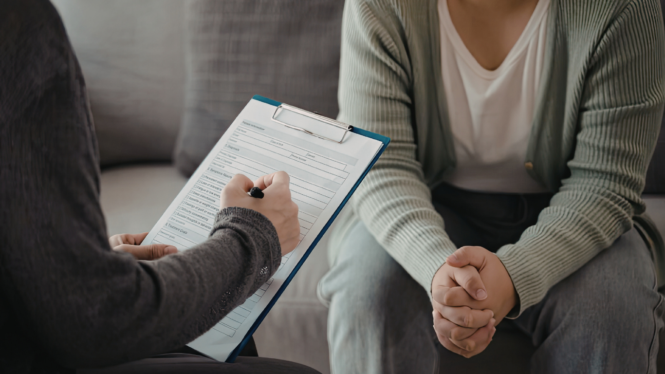 Person filling out medical or counseling form on clipboard during a consultation.