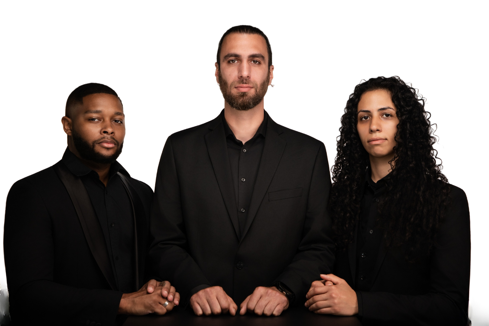 Three diverse people in black suits standing against a white background, facing the camera with serious expressions.