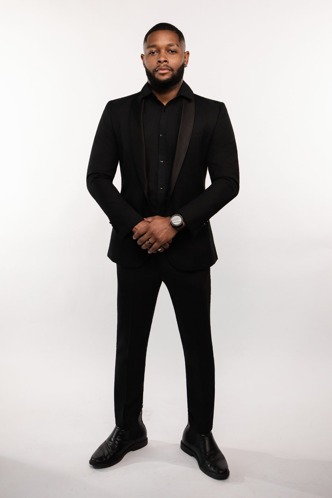 Man in black suit standing against white background
