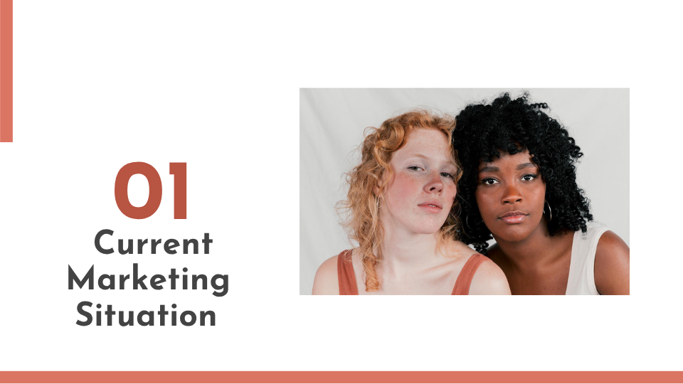 Two women, one with red curly hair and the other with black curly hair, sitting closely together against a white background.