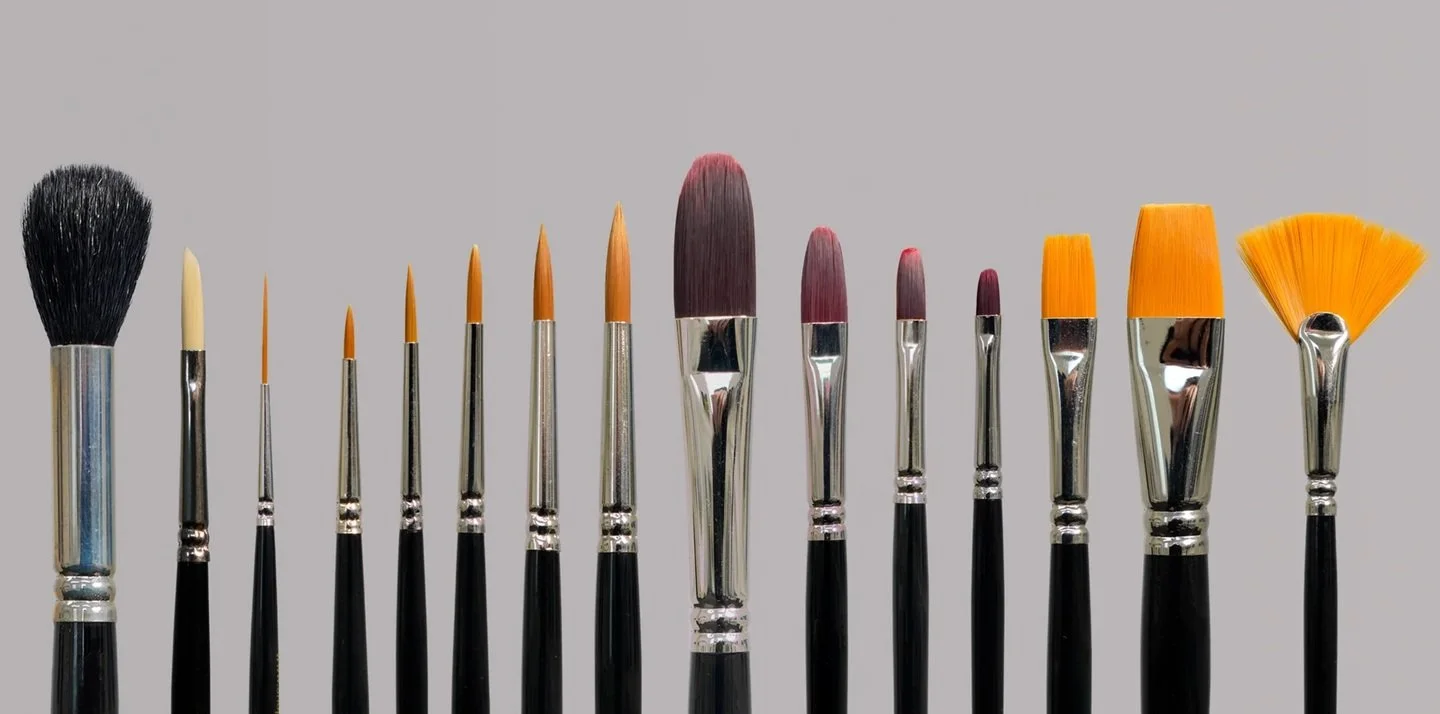 Darryn Eggleton signature paint brush set. A collaboration with Michael James Smith of Palettepro. A row of different paintbrushes with black handles lined up against a plain gray background.