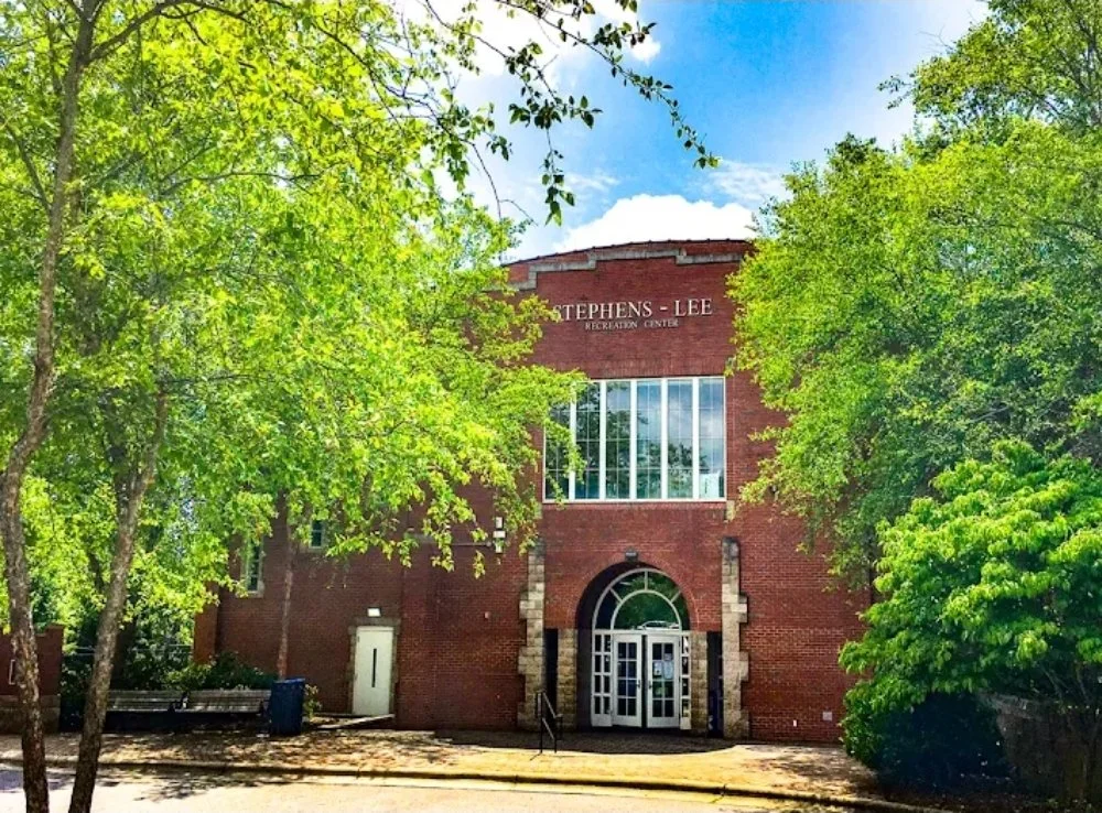 Brick building labeled 'Stephens-Lee Recreation Center' is surrounded by green trees under a partly cloudy sky.