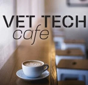 Close-up of a coffee cup with latte art on a wooden cafe counter at Vet Tech Cafe.