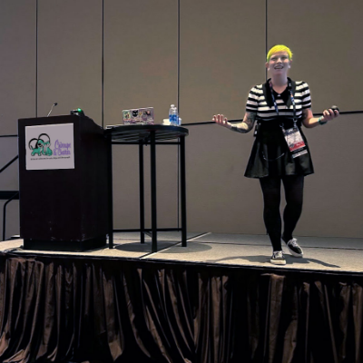 A woman with short yellow hair speaking on a stage about animal training
