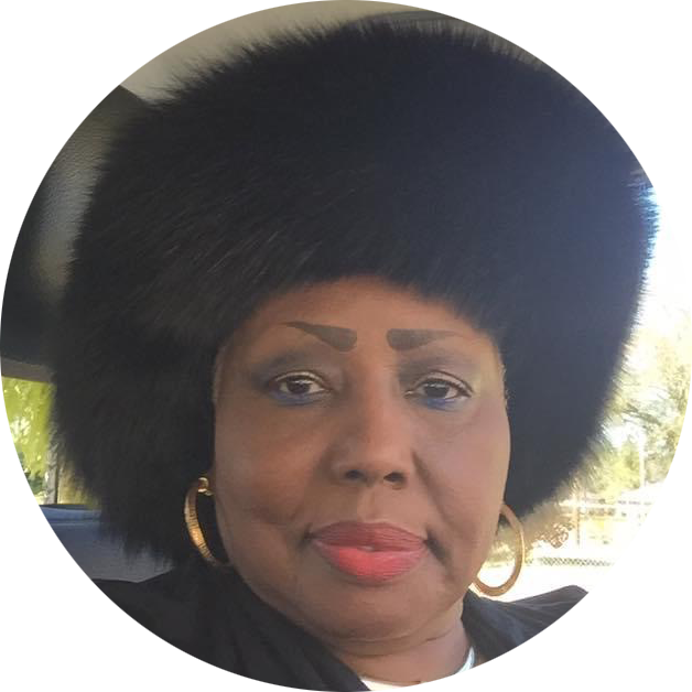 Portrait of a woman wearing a large black fur hat, gold hoop earrings, and red lipstick.