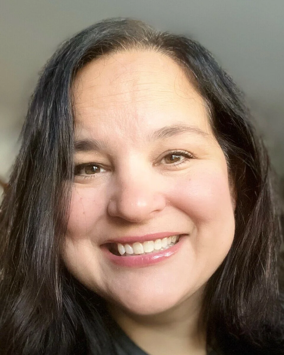 Close-up of a smiling woman with long dark hair and light skin.