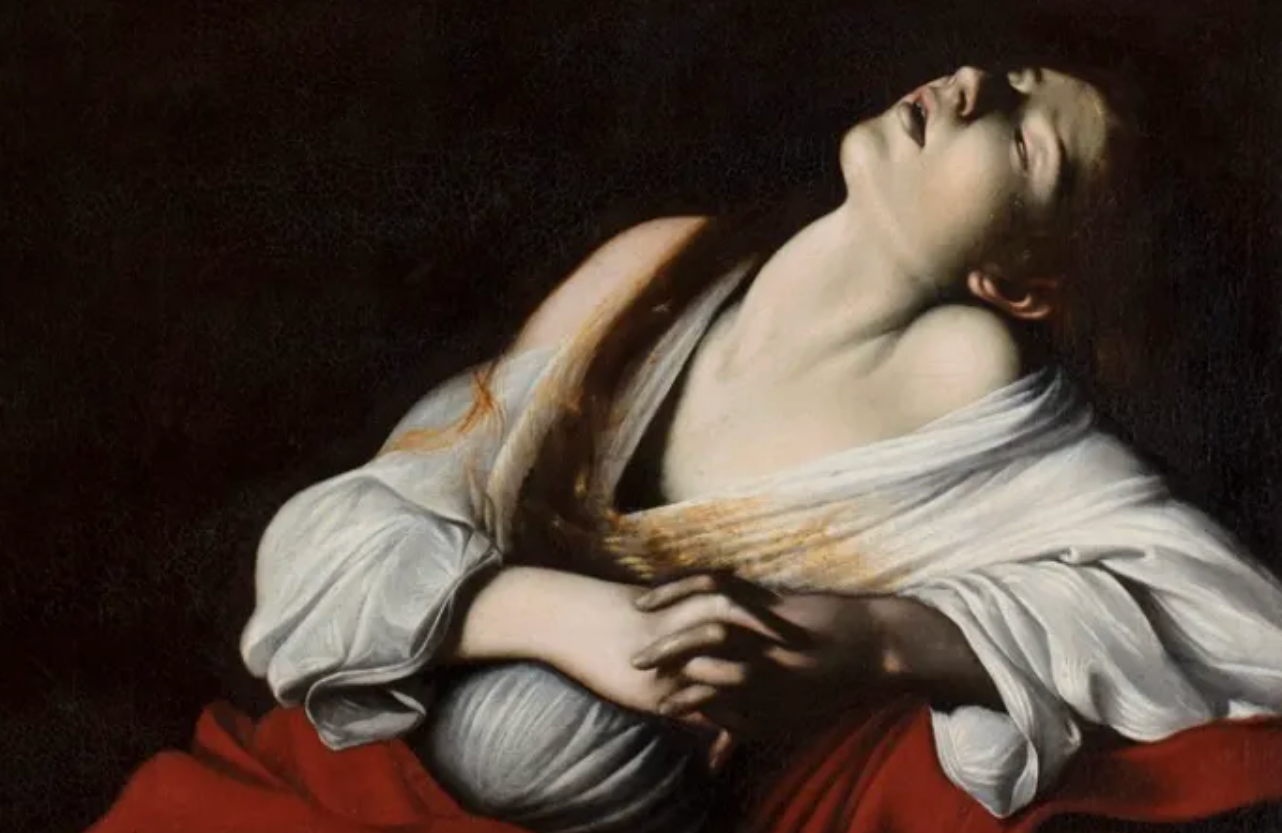 A person with long blond hair, wearing a white garment and red cloth, with their head tilted back and eyes closed, appearing to be in a dramatic or emotional pose.