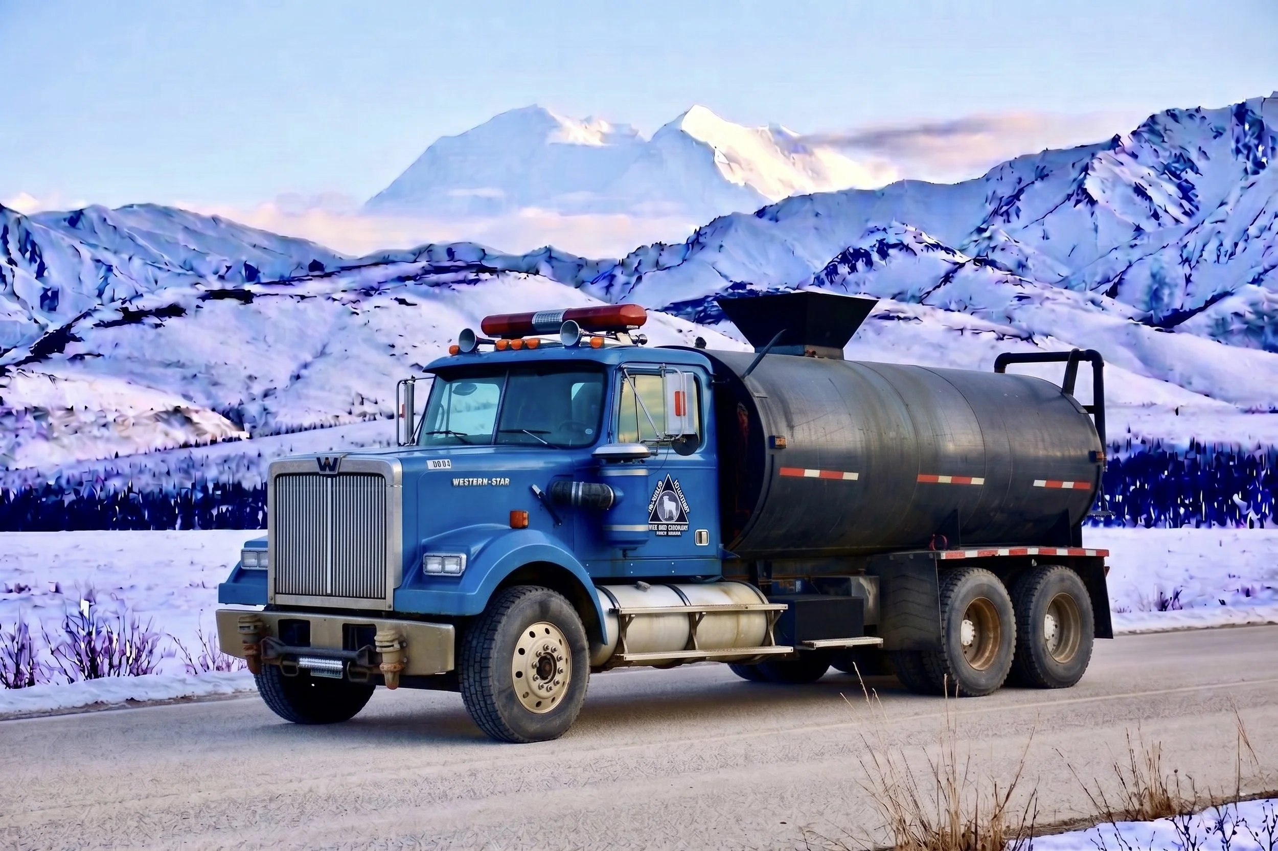 A blue utility truck driving on a snowy road with snow-covered mountains in the background.