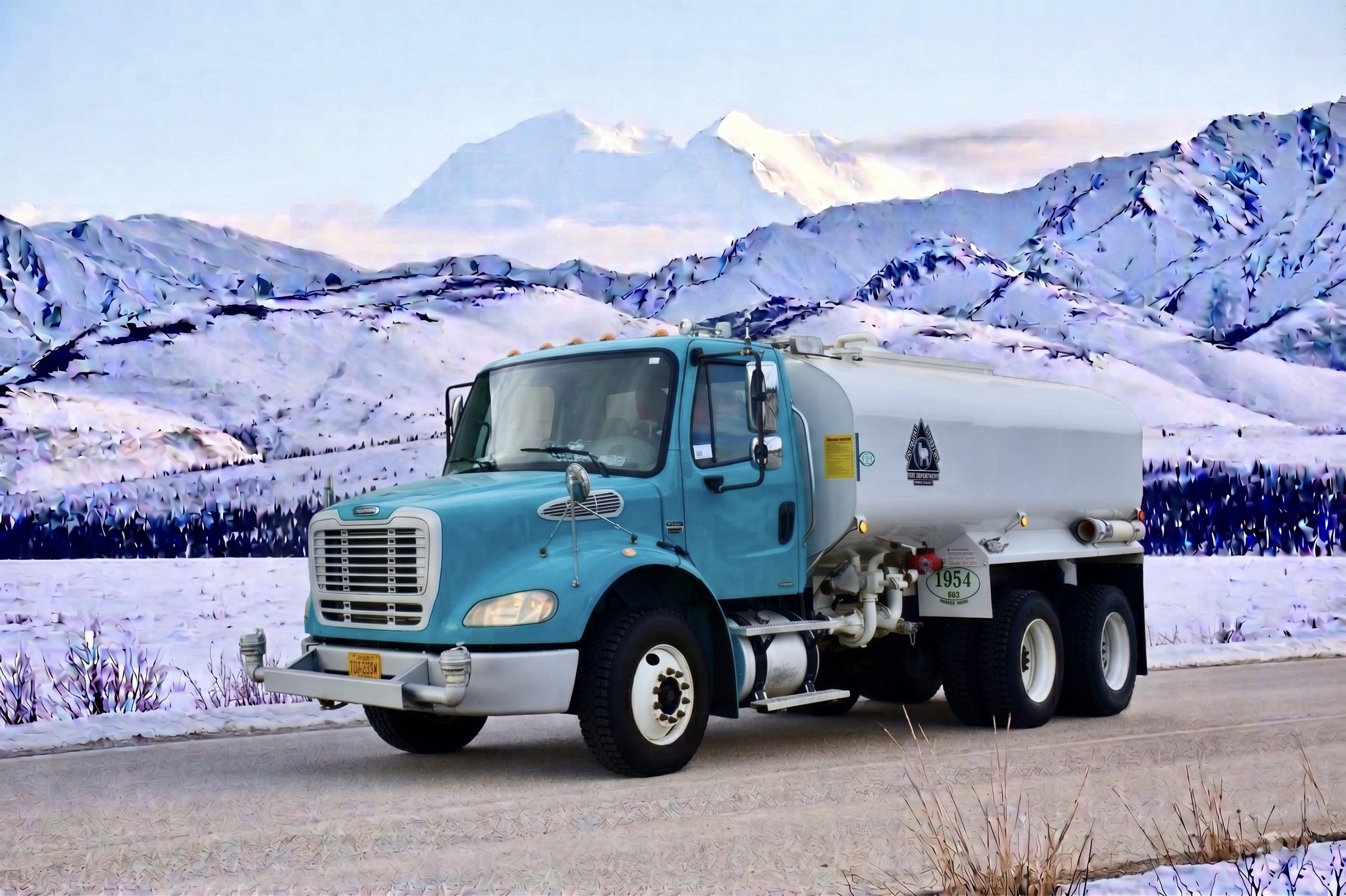 A blue utility truck parked on a snowy road with a mountain landscape in the background.