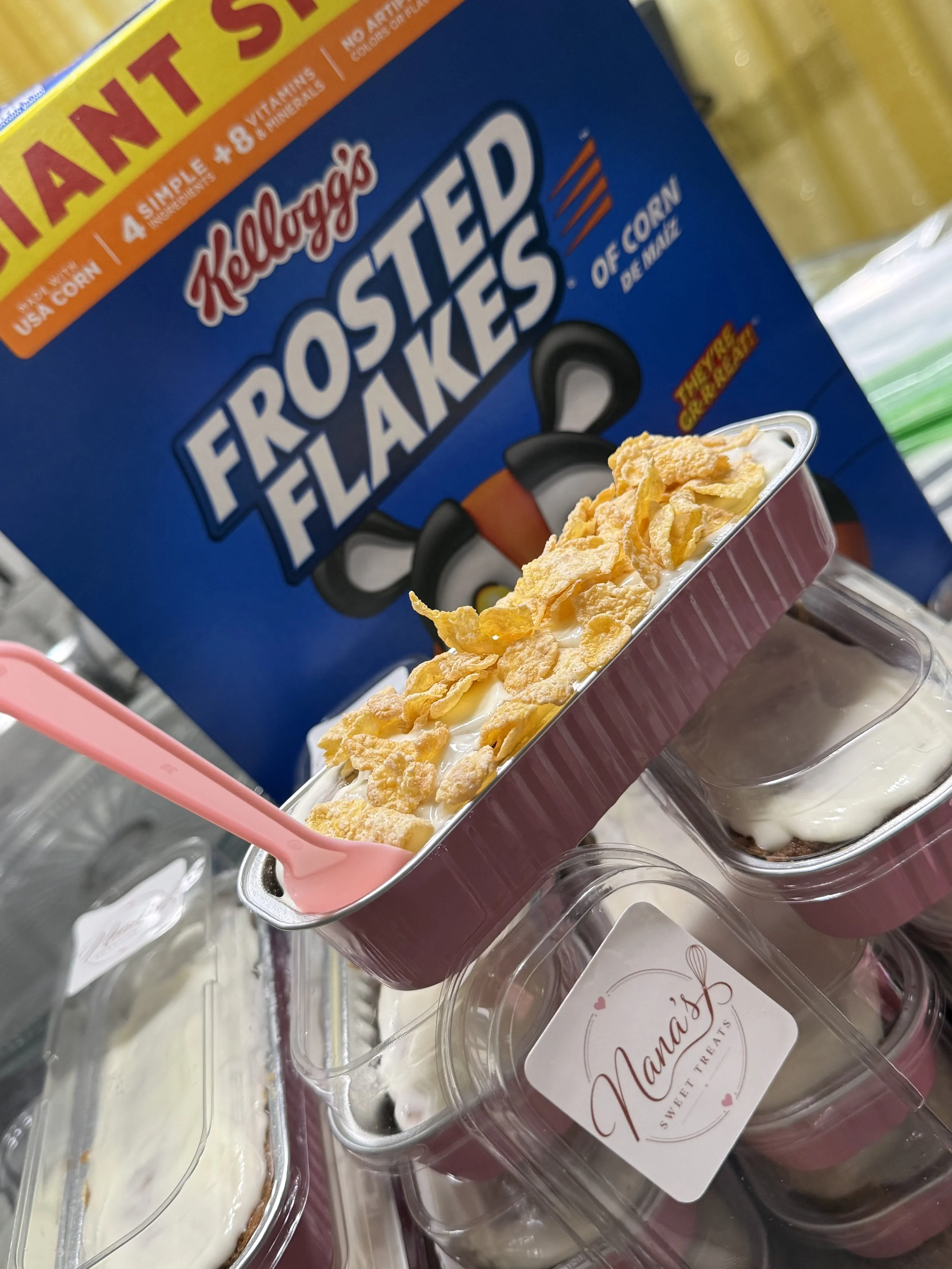 Close-up of a container of banana pudding with vanilla wafers on top, placed in front of a box labeled Kellogg's Froot Loops cereal.