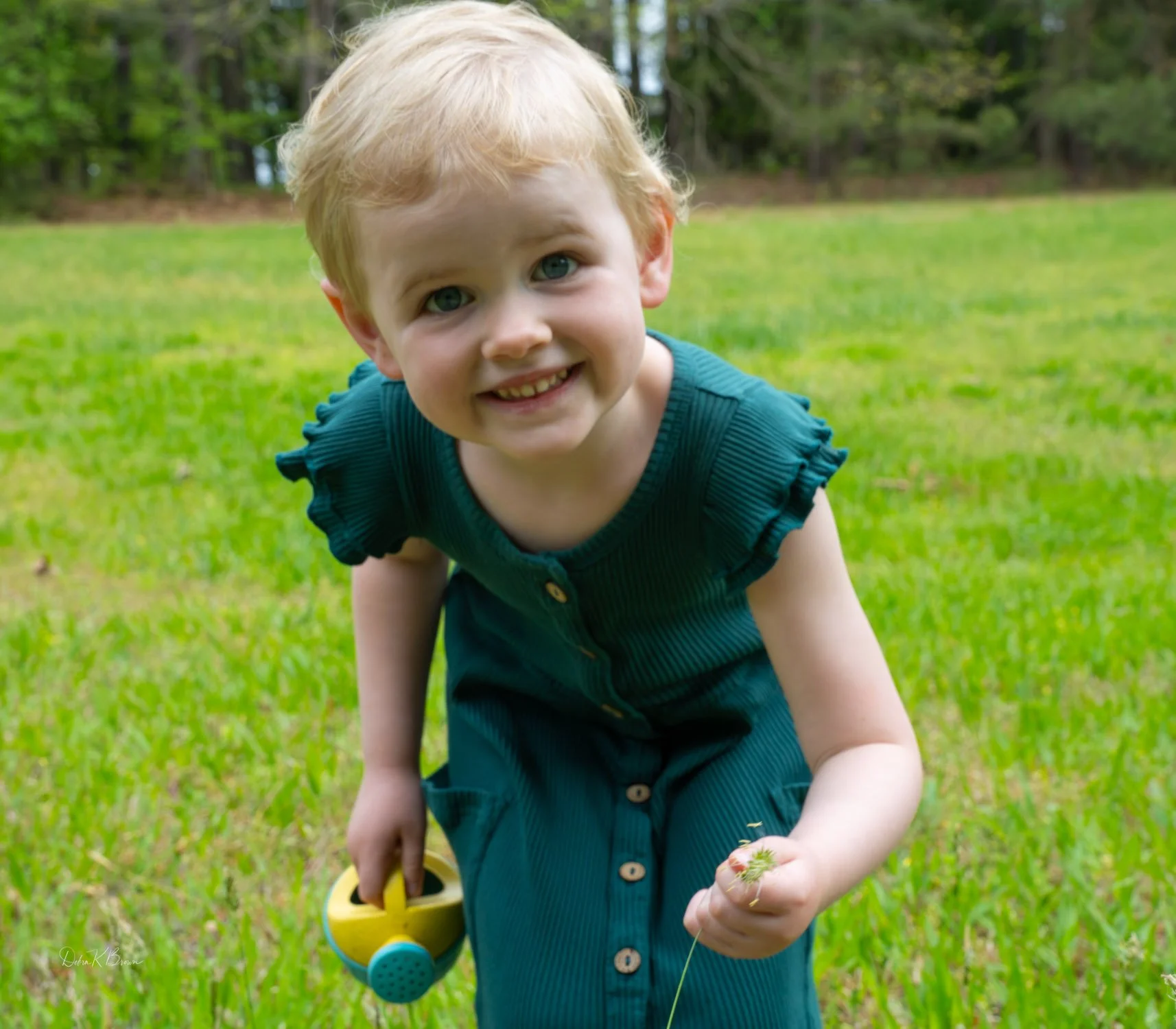 Smiling child holding apples while standing on grass