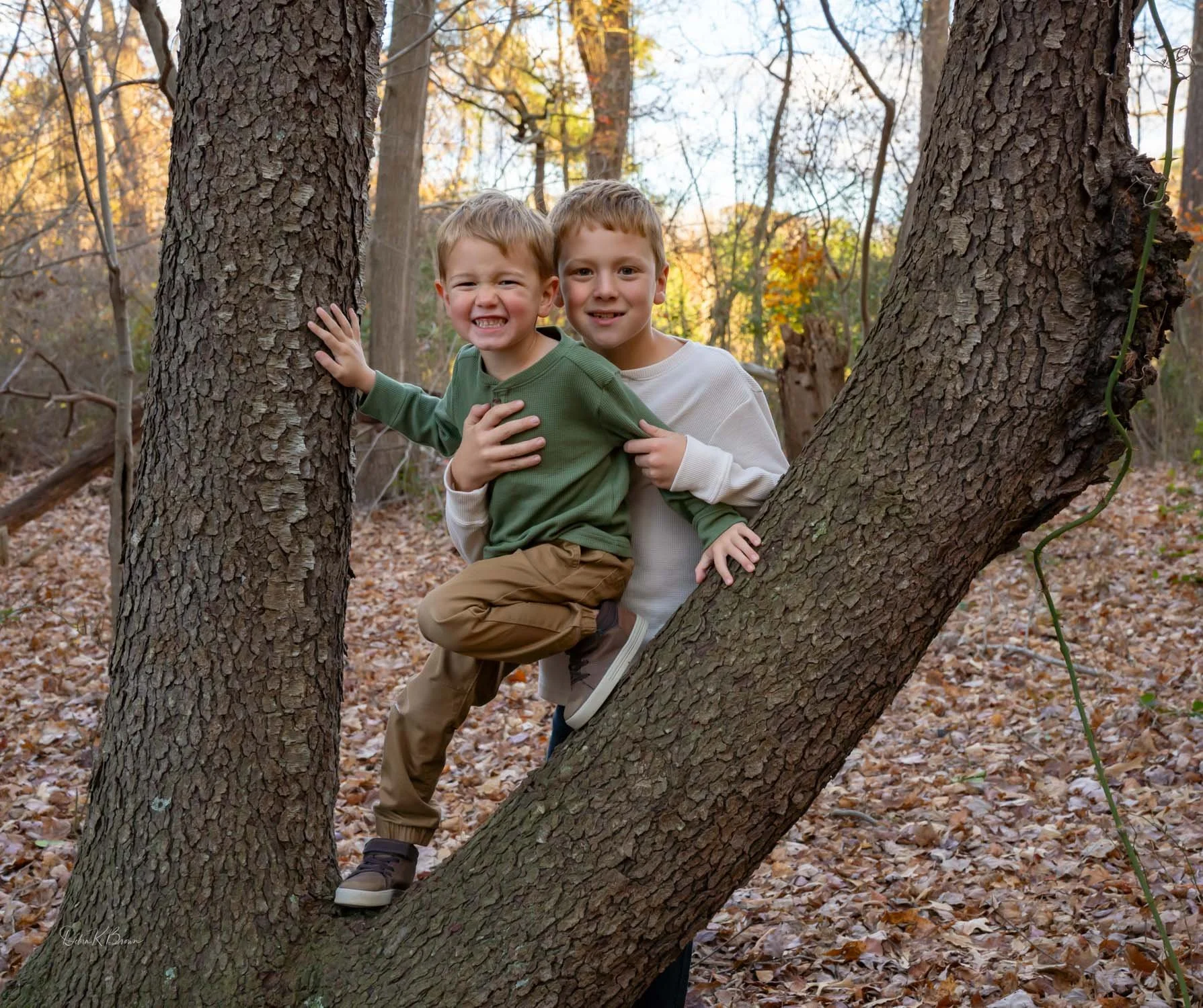 Two children hugging playfully among trees in the wo