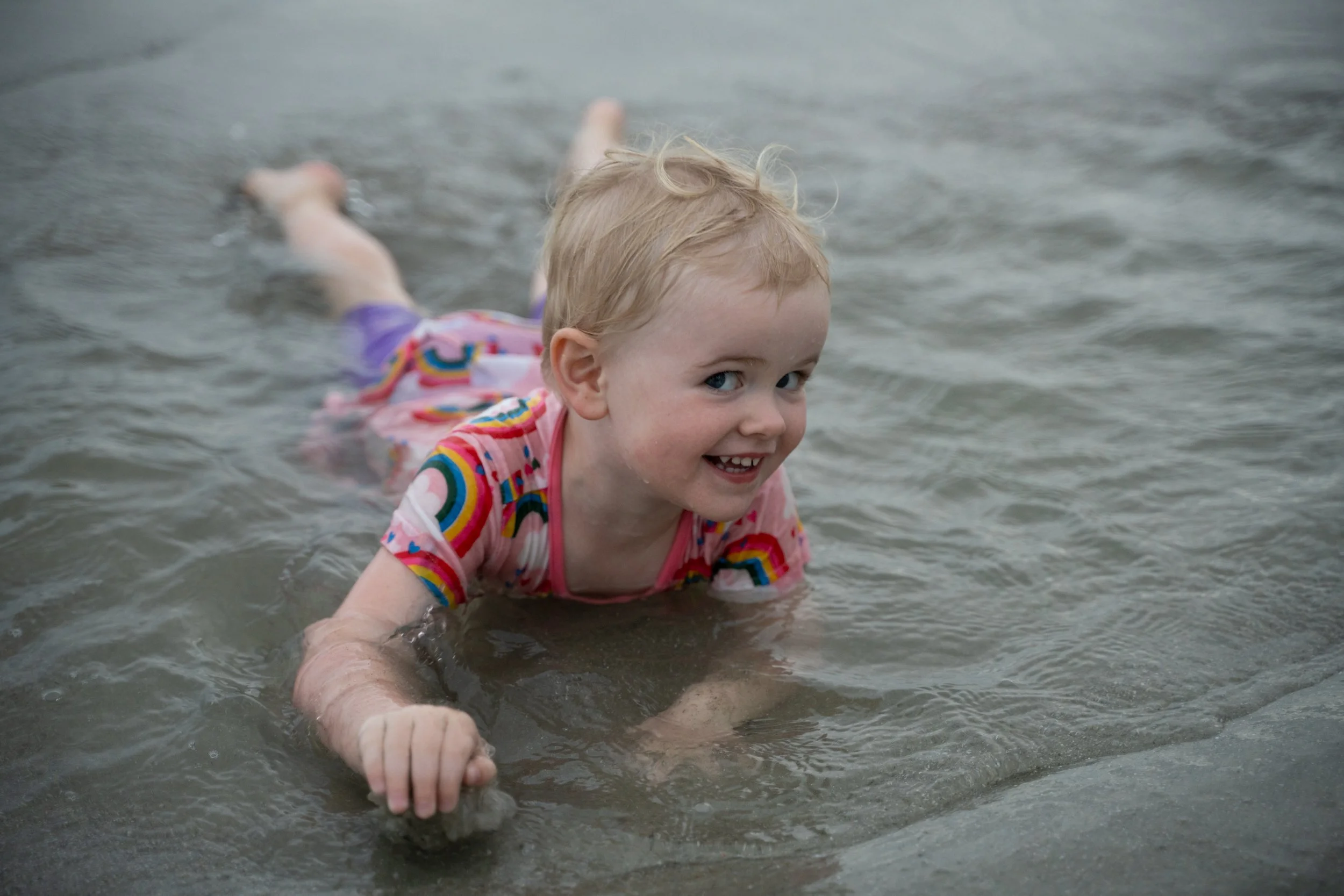 Young child smiling while playing in shallow water