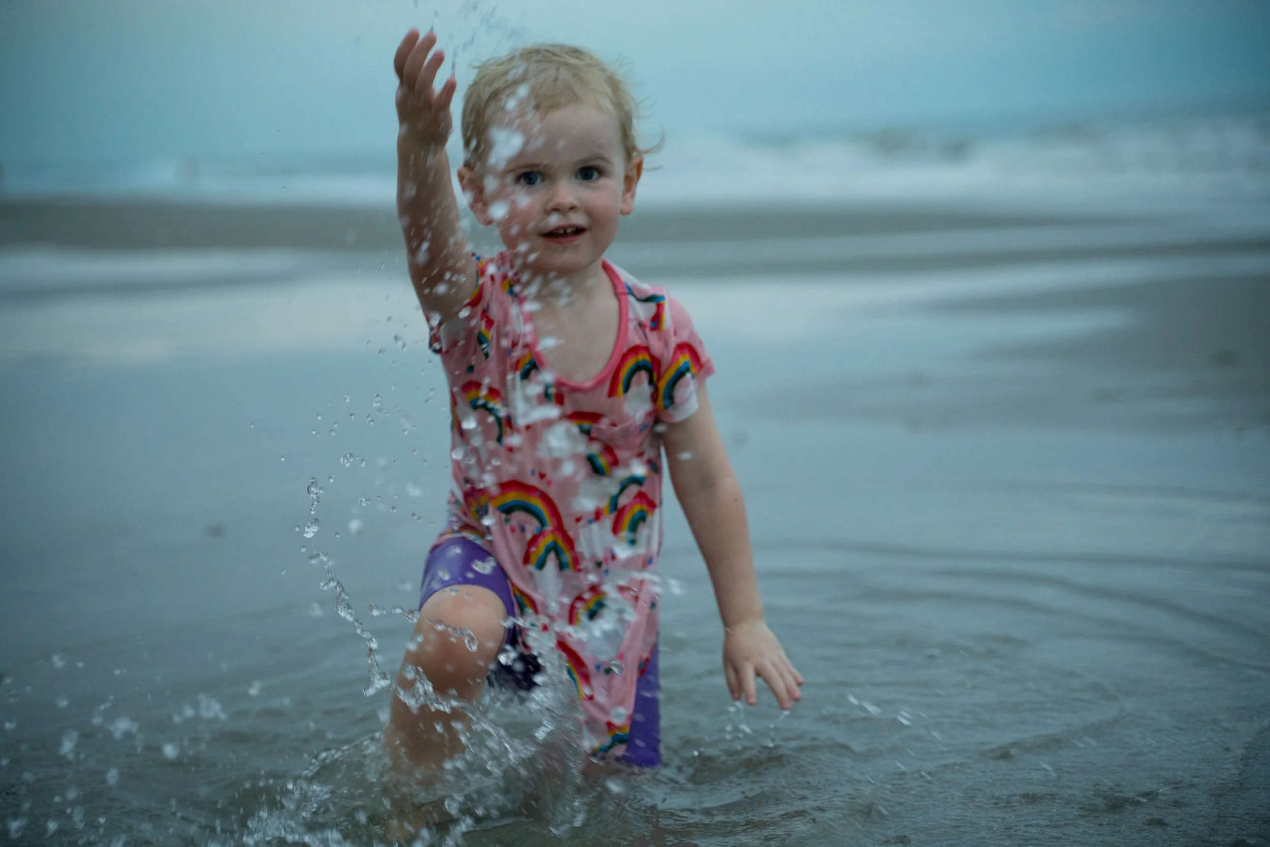 Child splashing in water in a floral swimsuit