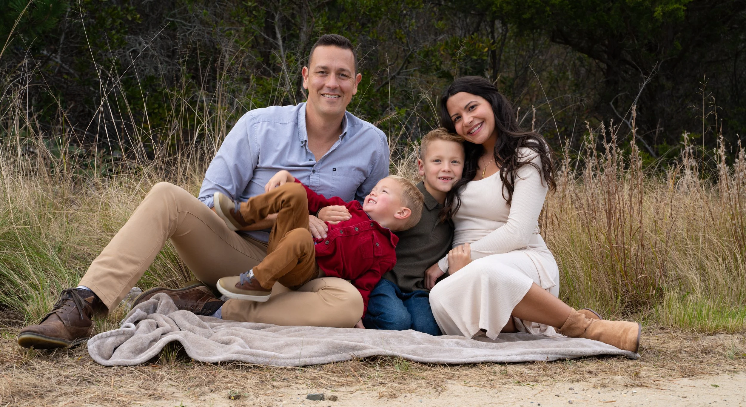 Family sitting on ground with two children in a relaxed outdoor setting