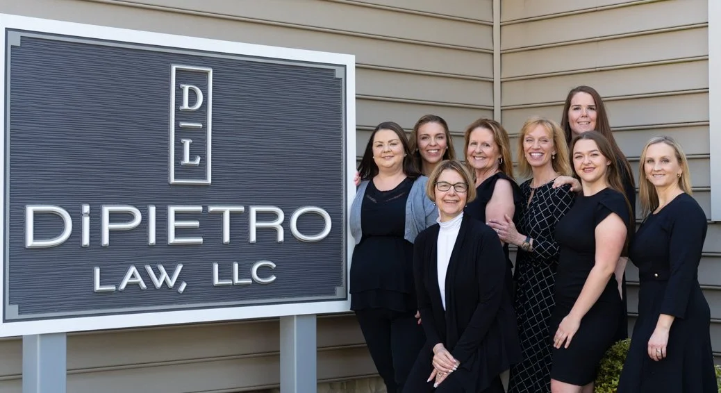 Corporate group posing outside office building with branded sign