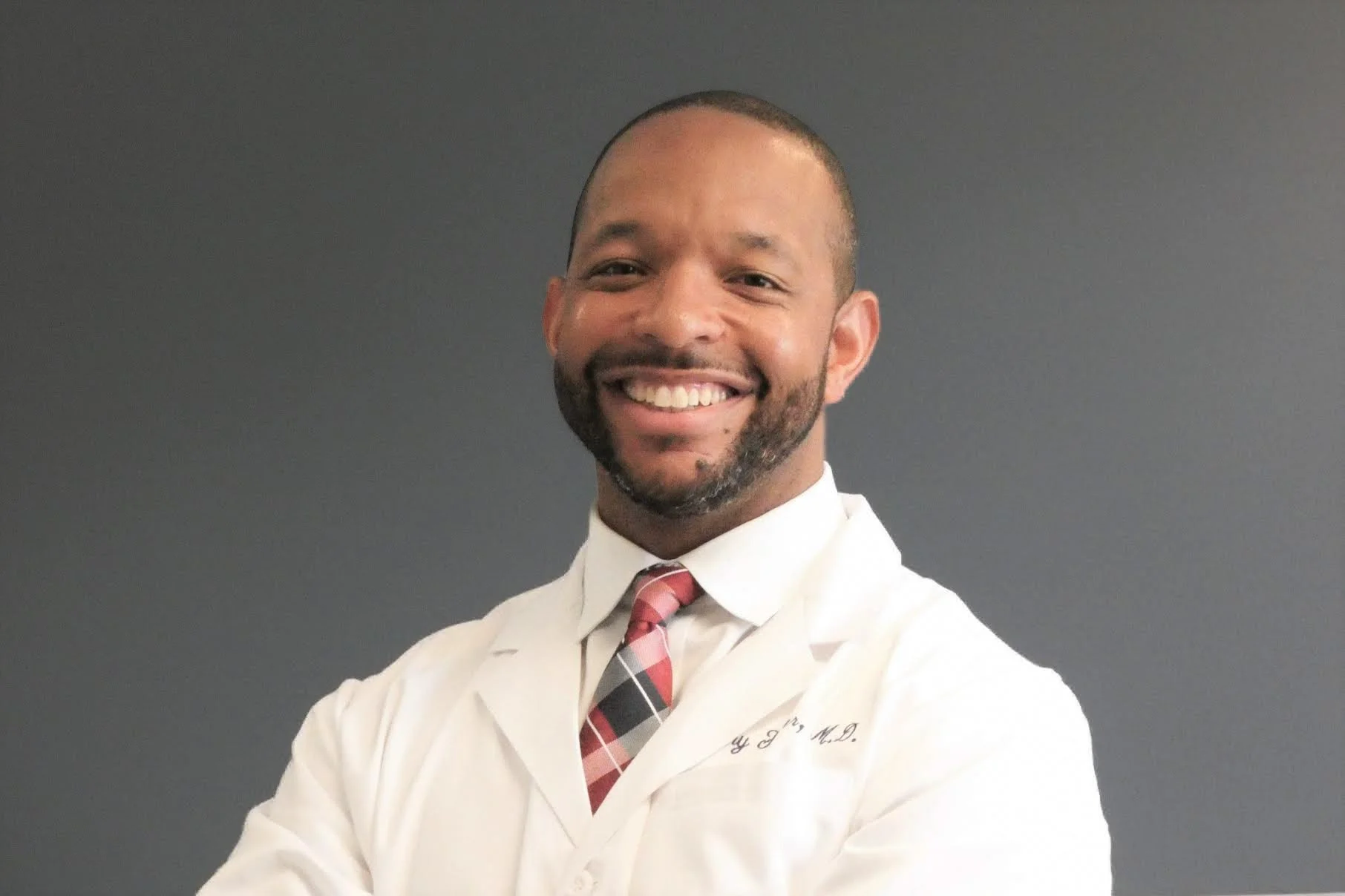 Man in white medical coat with bow tie, smiling confidently