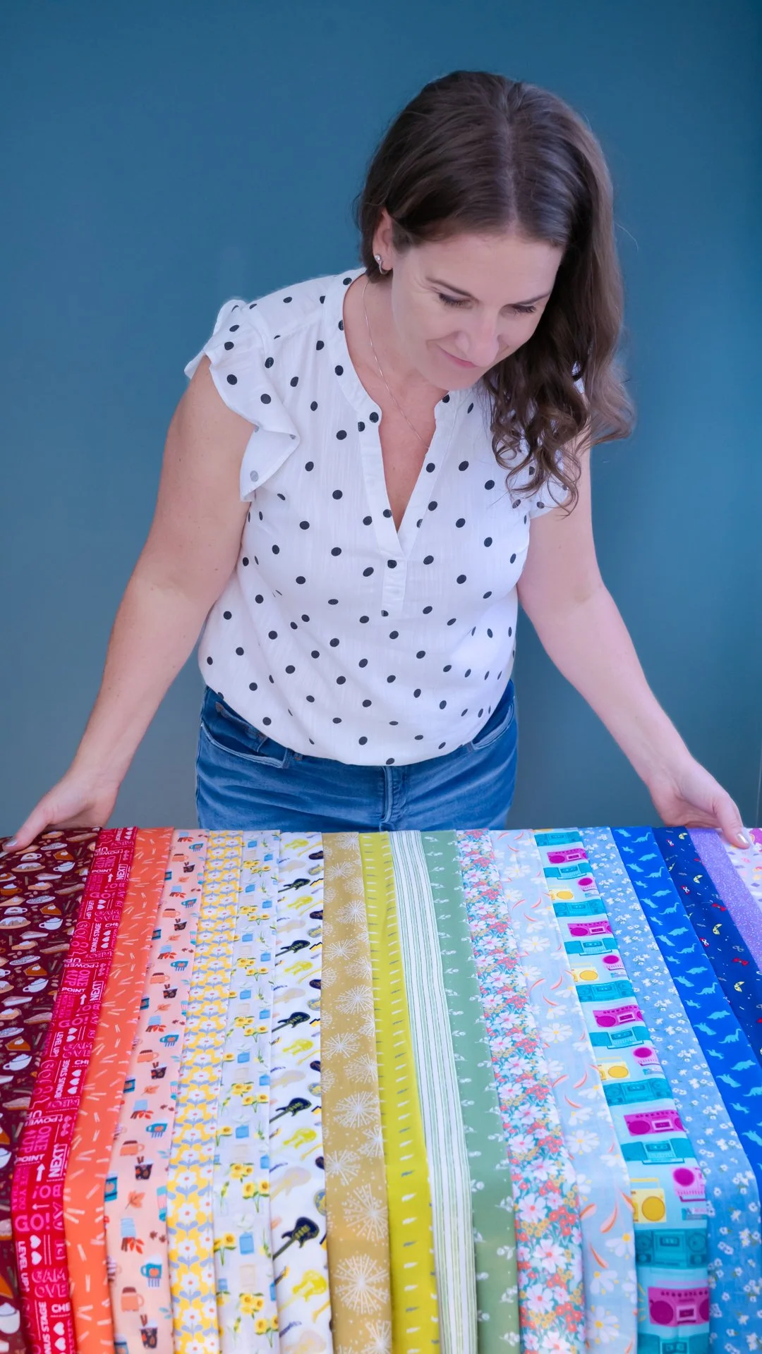 Woman looking at colorful fabric options laid out on a table.