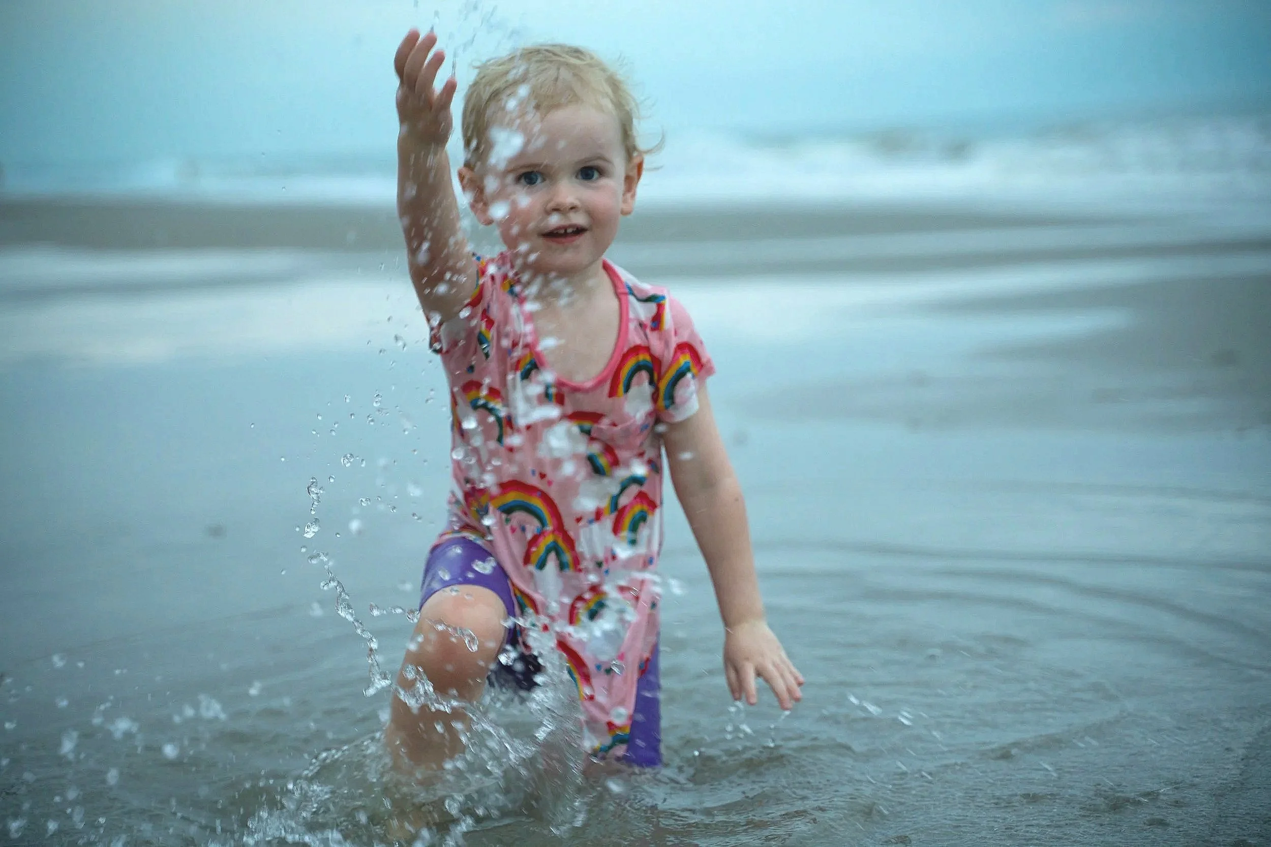 Child splashing in water in a floral swimsuit