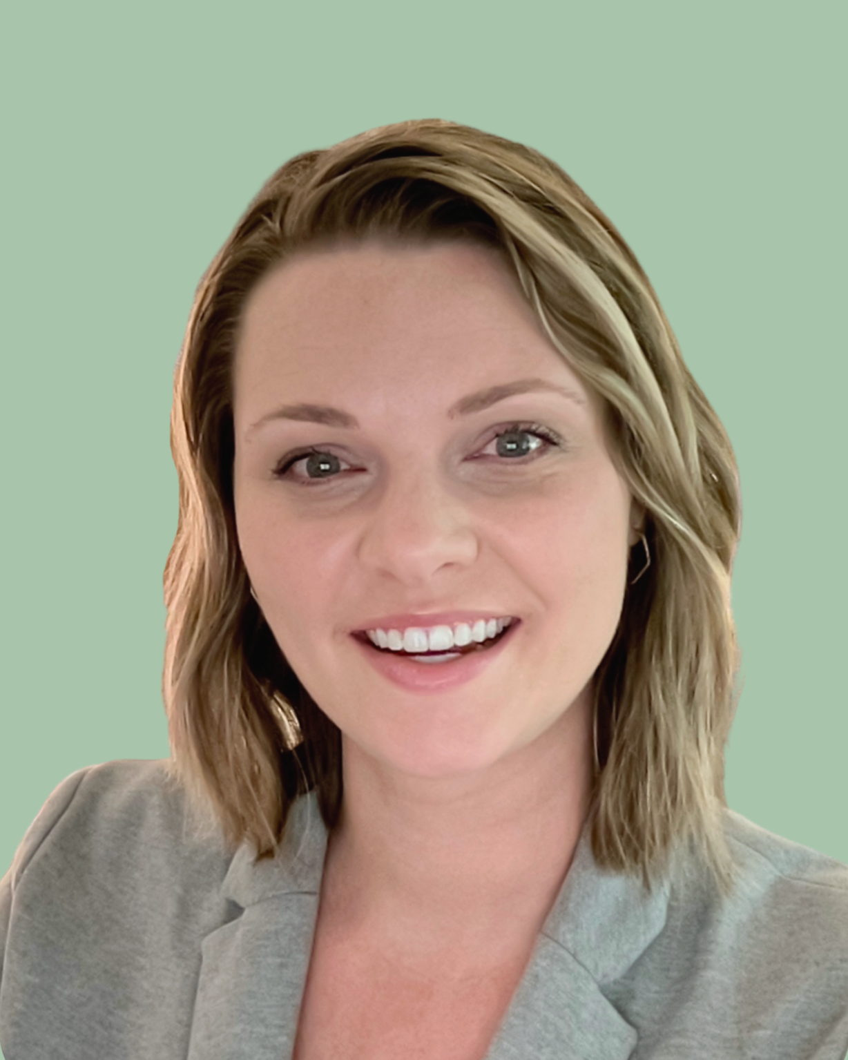 Portrait of a smiling woman with shoulder-length wavy blonde hair, wearing a light gray blazer, against a solid light green background.