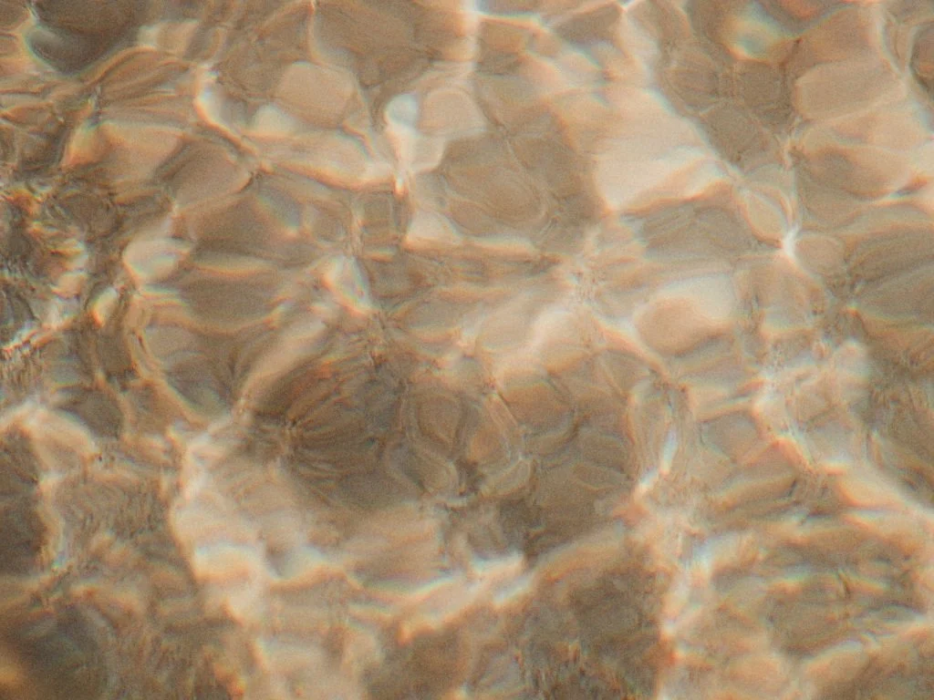 Close-up view of rippling water with sunlight reflections creating a textured pattern.