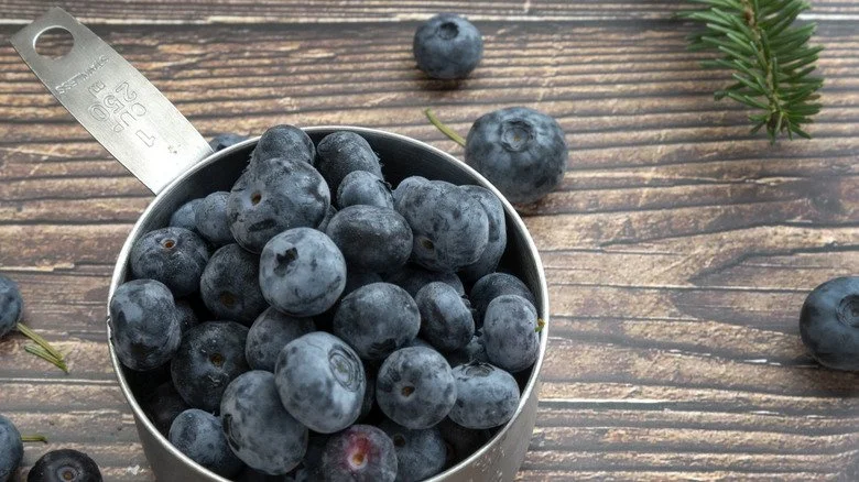 Blueberries in a measuring cup on a wooden table