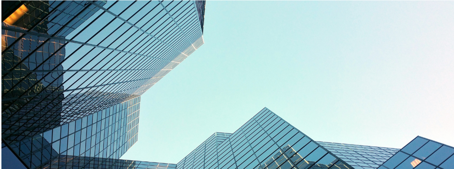 Looking up at tall modern glass skyscrapers against a clear sky.