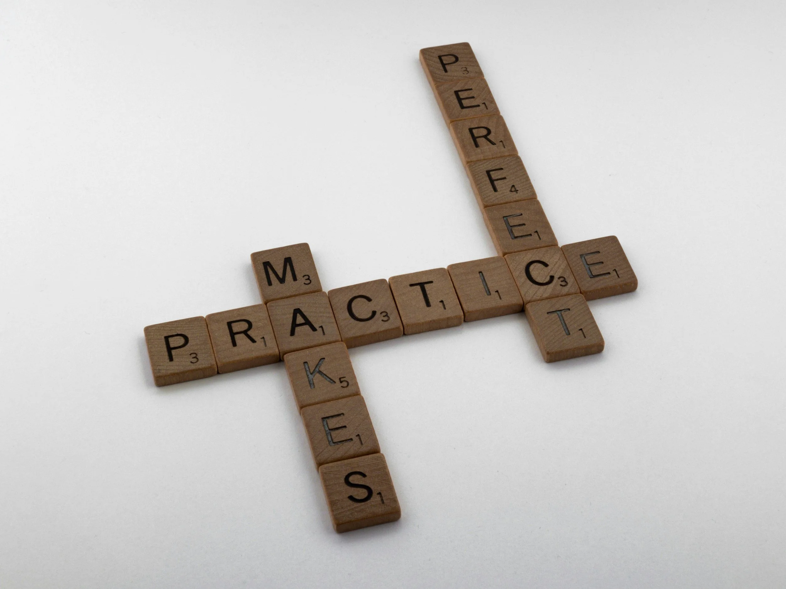 Wooden Scrabble blocks spell out 'PEACE' and 'MEDITATE' on a white background.